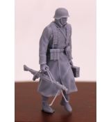 Voják Wehrmachtu kráčící v zimním kabátě s ocelovou helmou, kulometem MG 42 a bednou s kulometem